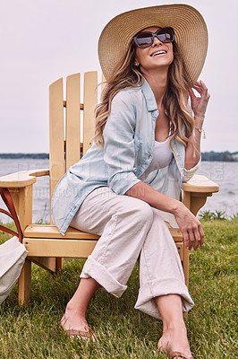 Buy stock photo Shot of a beautiful young woman relaxing on a chair next a lake