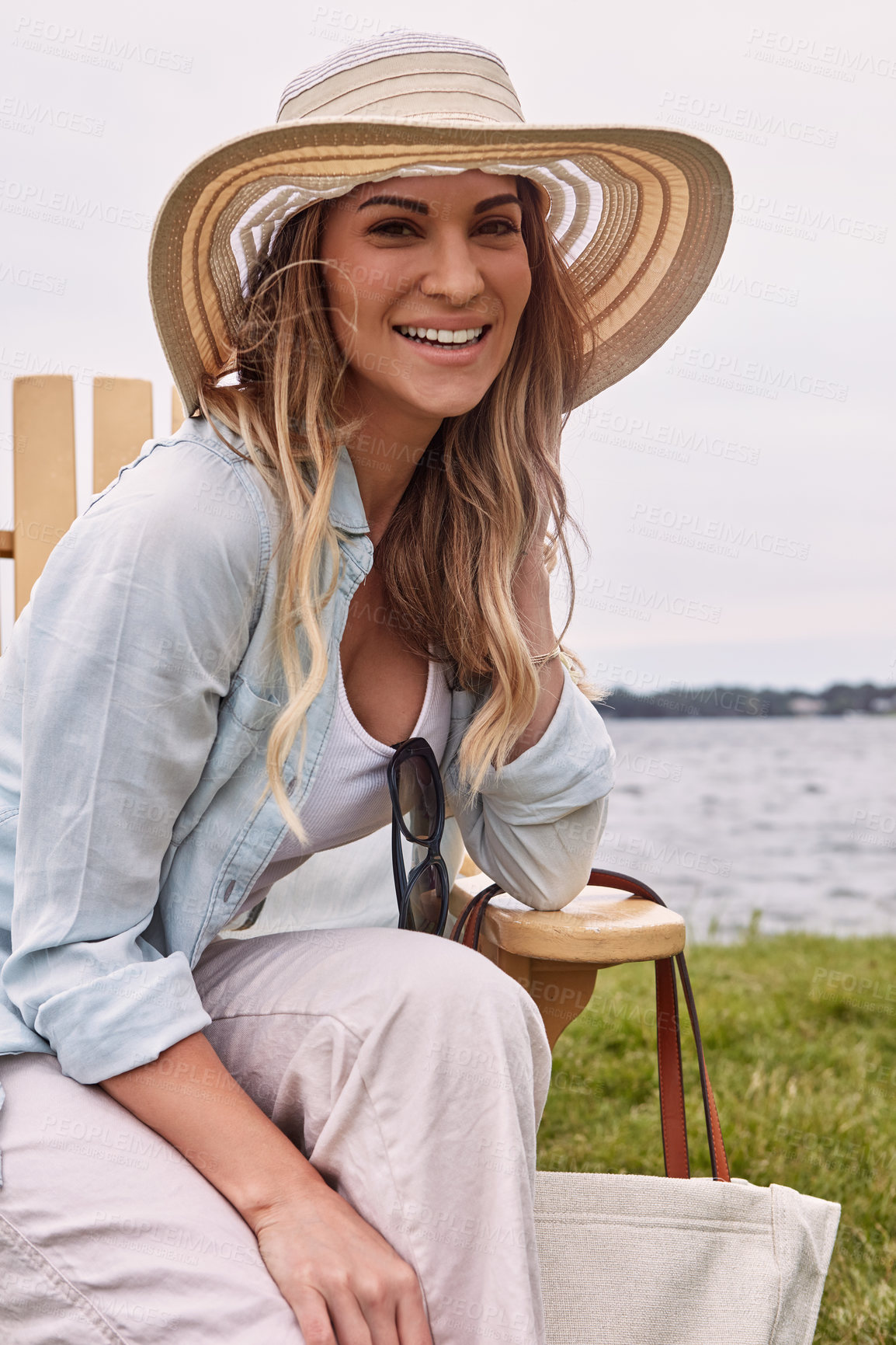 Buy stock photo Shot of a beautiful young woman relaxing on a chair next a lake