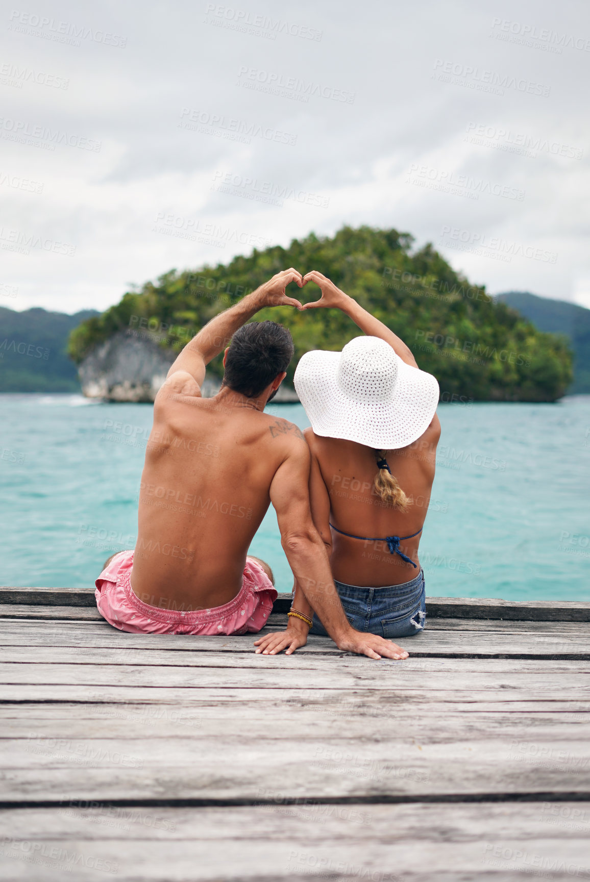 Buy stock photo Heart shape, hands and couple by ocean while on a summer, romantic and tropical vacation. Island, dock and back of man and woman relaxing on wood pier with love gesture on holiday or weekend trip.