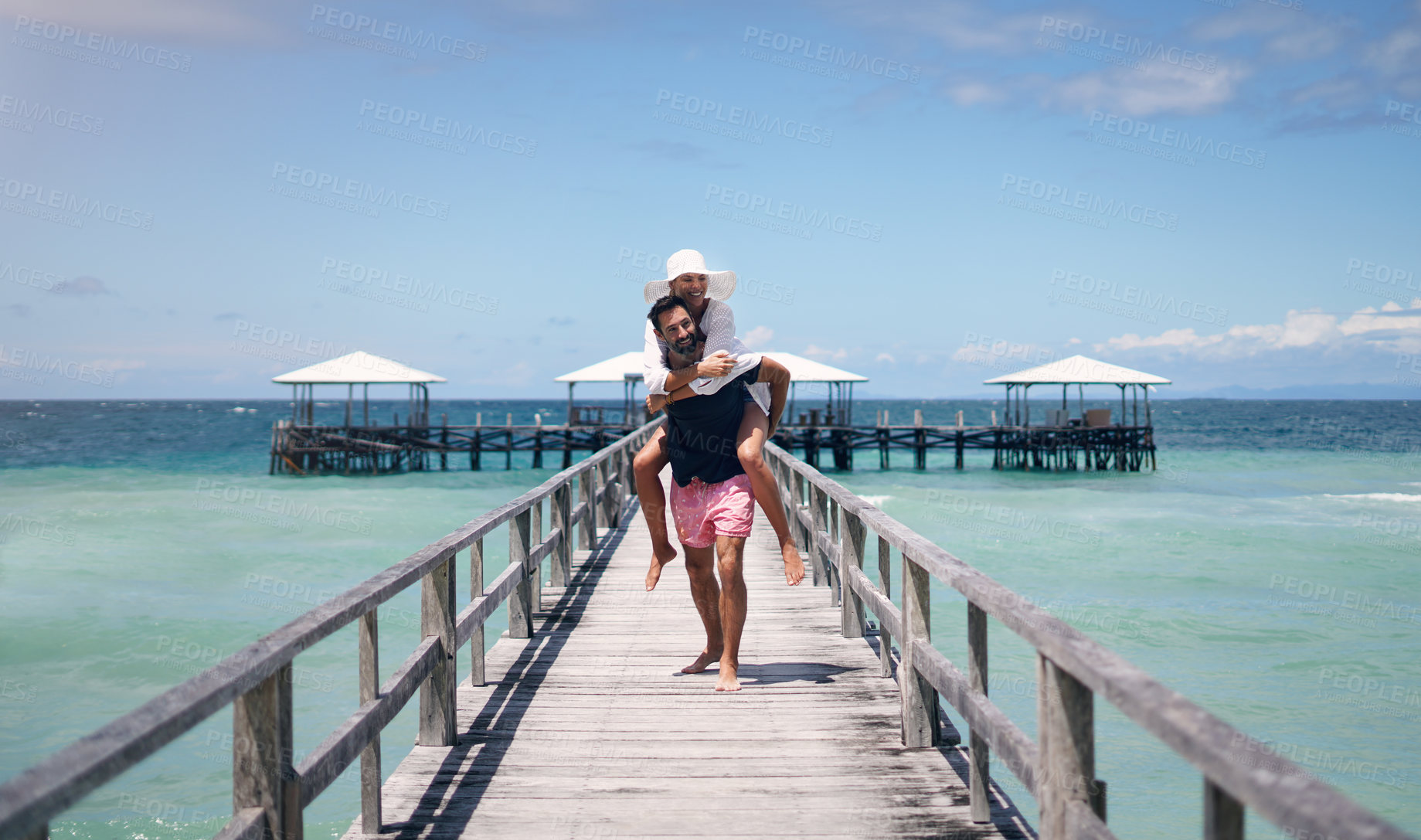 Buy stock photo Couple, piggyback and outdoor beach deck on a tropical island with love and water on holiday. Summer vacation, travel smile and Maldives playful in nature with freedom and happiness by ocean and sea