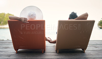 Buy stock photo Rearview shot of an unrecognizable couple sitting on sun loungers together and holding hands while on vacation