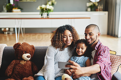 Buy stock photo Cropped shot of a happy young family of three taking selfies together in their living room at home