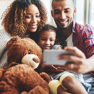 Buy stock photo Cropped shot of a happy young family of three taking selfies together in their living room at home