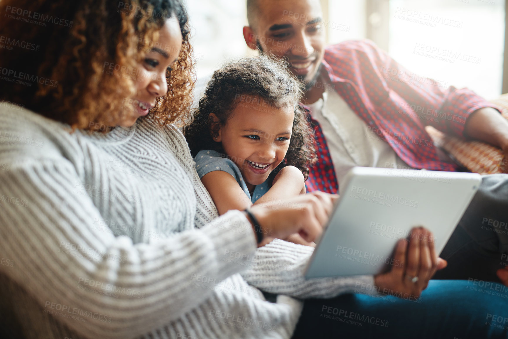 Buy stock photo Cropped shot of an adorable little girl using a digital tablet with her parents in their living room at home