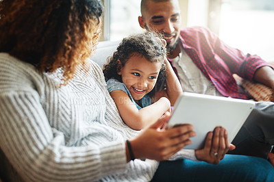 Buy stock photo Cropped shot of an adorable little girl using a digital tablet with her parents in their living room at home