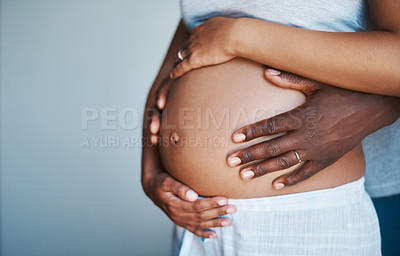 Buy stock photo Cropped shot of an unrecognizable man holding his pregnant wife's belly at home