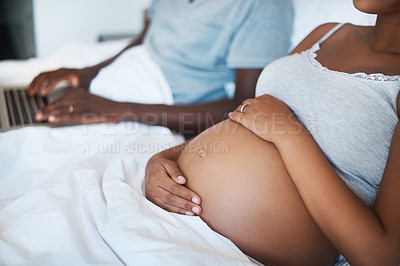Buy stock photo Cropped shot of an unrecognizable man using a laptop while sitting bed with his pregnant wife