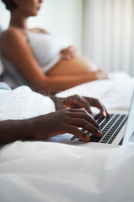 Buy stock photo Cropped shot of an unrecognizable man using a laptop while sitting bed with his pregnant wife