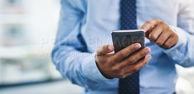 Buy stock photo Cropped shot of an unrecognizable businessman standing alone in the office and using his cellphone to text