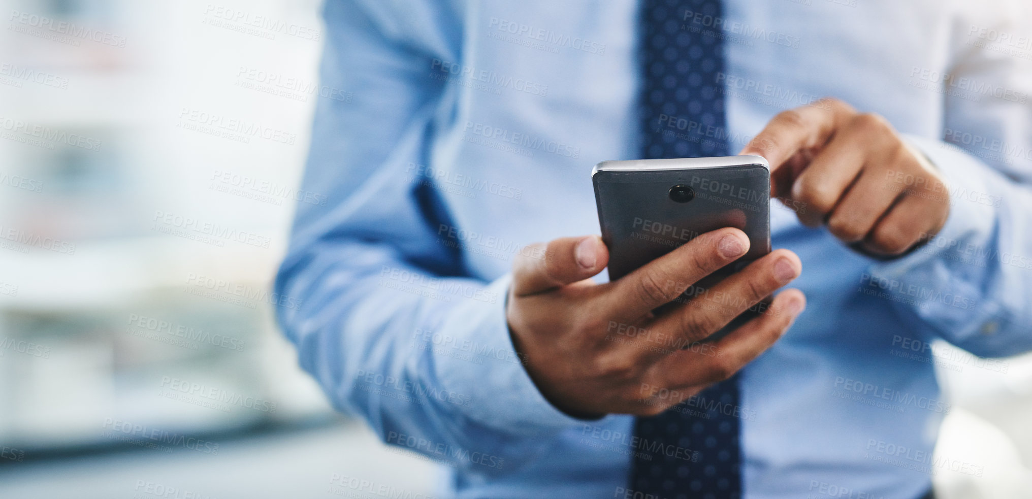 Buy stock photo Cropped shot of an unrecognizable businessman standing alone in the office and using his cellphone to text