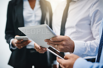 Buy stock photo Cropped shot of an unrecognizable group of businesspeople standing together and using technology in the office