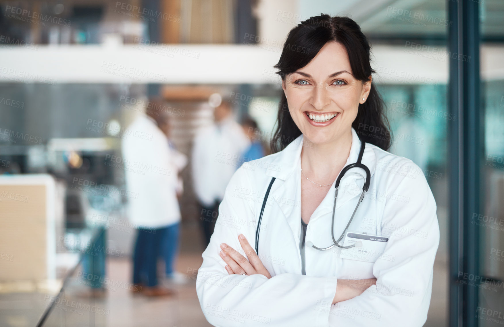 Buy stock photo Portrait of a confident doctor working in a hospital with her colleagues in the background