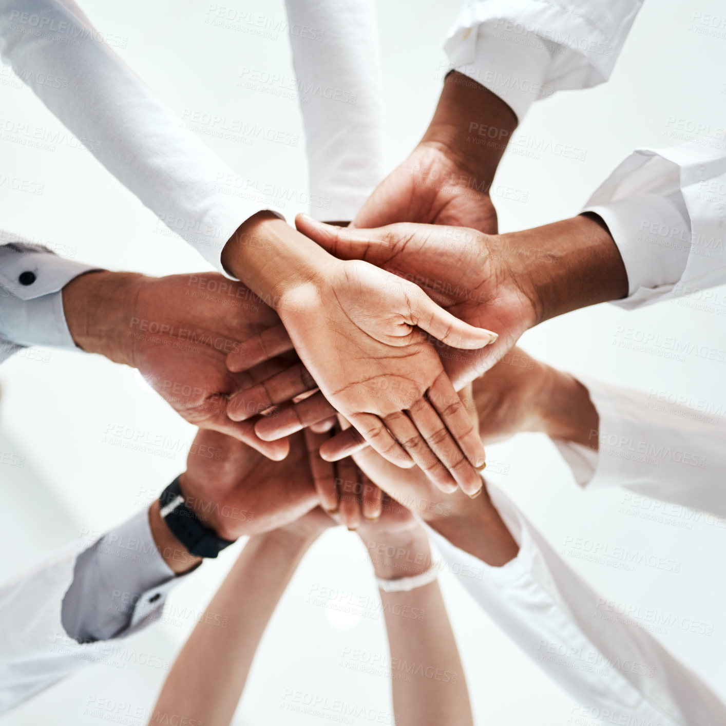 Buy stock photo Low angle shot of a diverse team of doctors joining their hands together in a hospital