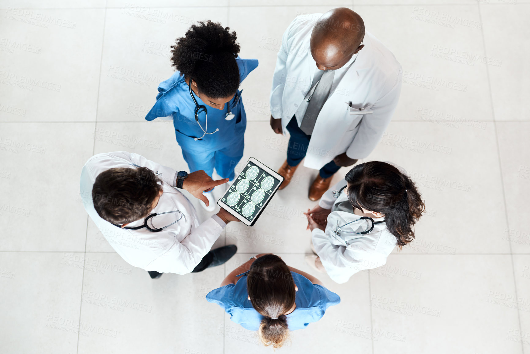 Buy stock photo High angle shot of a team of doctors using a digital tablet to discuss an x ray in a hospital
