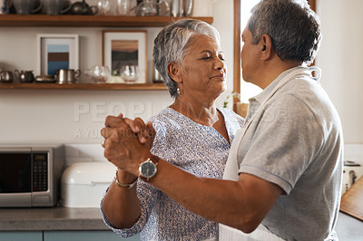 Buy stock photo Shot of a happy mature couple dancing together while cooking in the kitchen at home