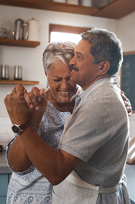 Buy stock photo Shot of a happy mature couple dancing together while cooking in the kitchen at home