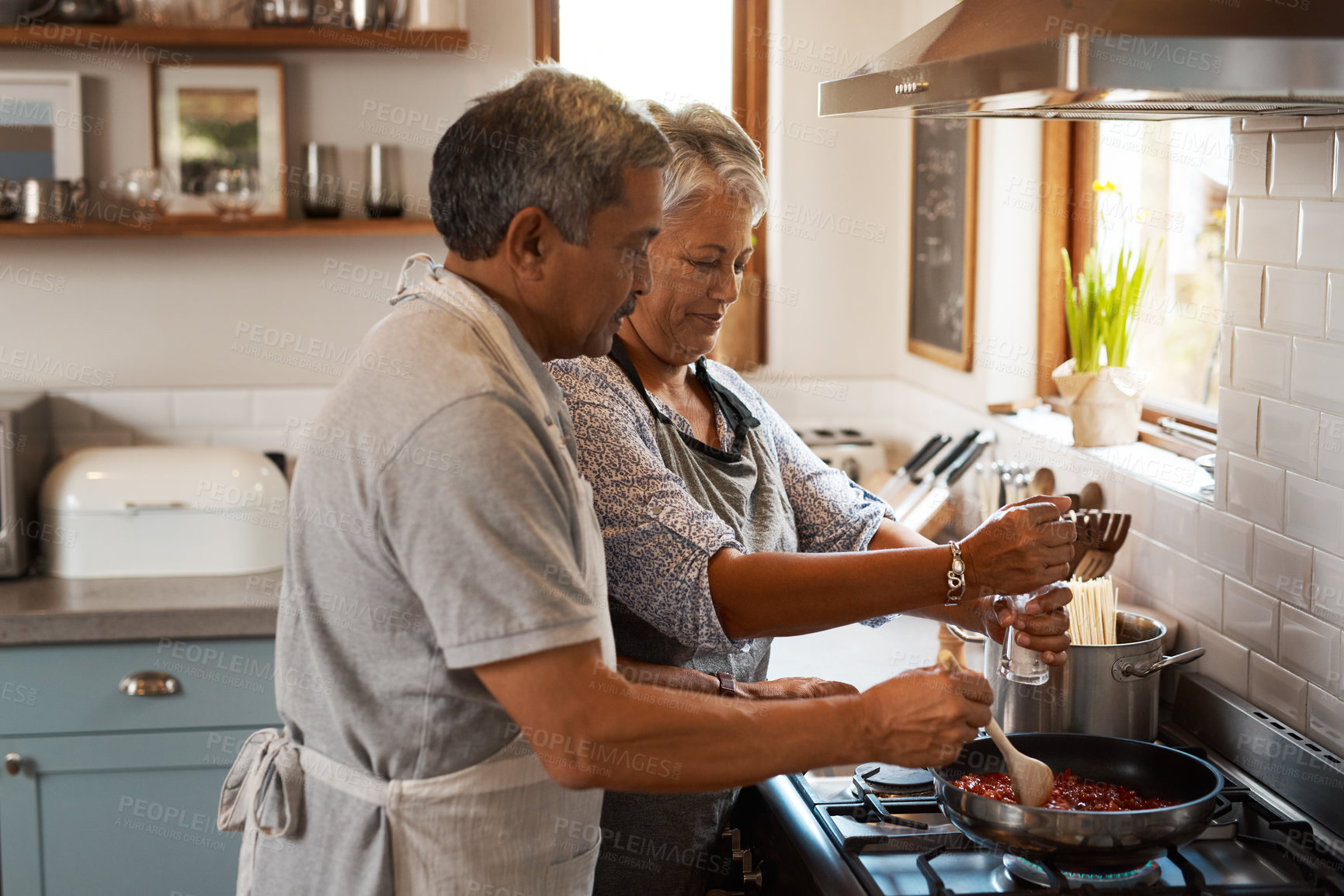 Buy stock photo Cooking food, help and old couple in kitchen with smile, meal prep and frying at stove together. Love, senior woman helping elderly man prepare lunch in pan, retirement and dinner time in modern home