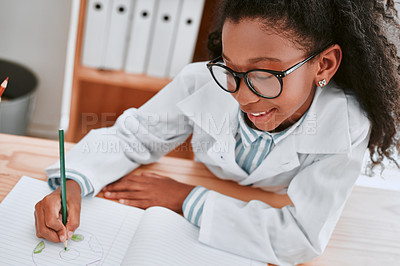 Buy stock photo Shot of an adorable young school girl drawing a diagram in her exercise book in science class at school