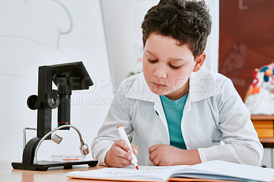 Buy stock photo Shot of an adorable young school boy writing notes in his note book in science class at school