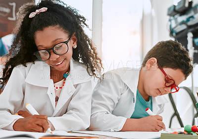 Buy stock photo Shot of two adorable young school pupils writing notes in their workbooks in science class at school