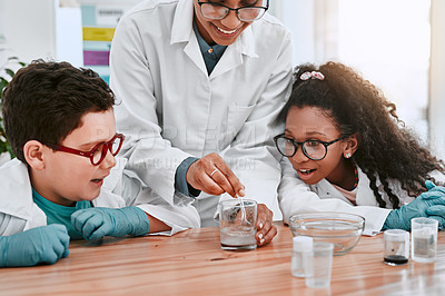 Buy stock photo Shot of two adorable young school pupils doing an experiment with their science teacher at school