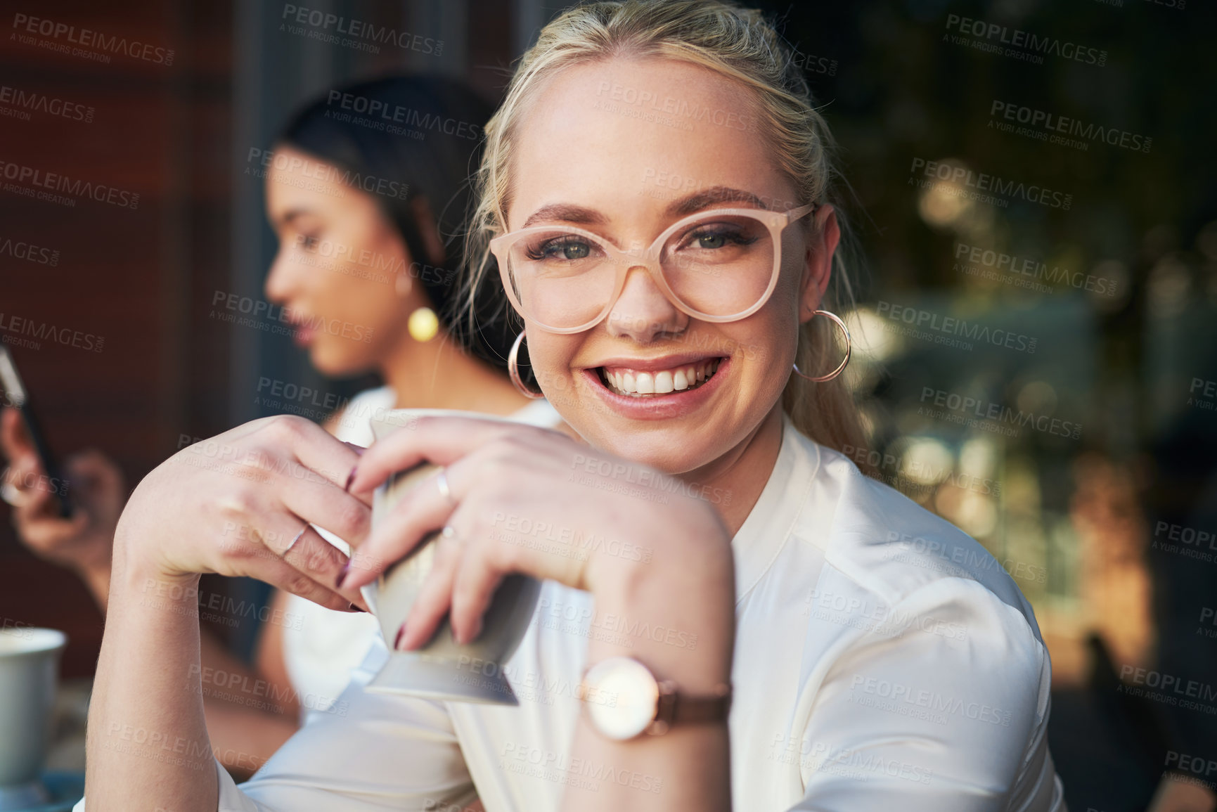Buy stock photo Defocused shot of a young woman enjoying a cup of coffee at a cafe