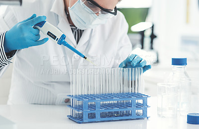 Buy stock photo Cropped shot of an unrecognizable female scientist transferring a liquid sample from a dropper into test tubes while working in a laboratory
