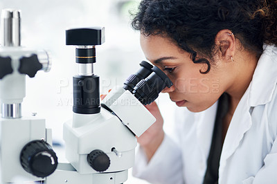 Buy stock photo Cropped shot of a young female scientist using a microscope in a laboratory