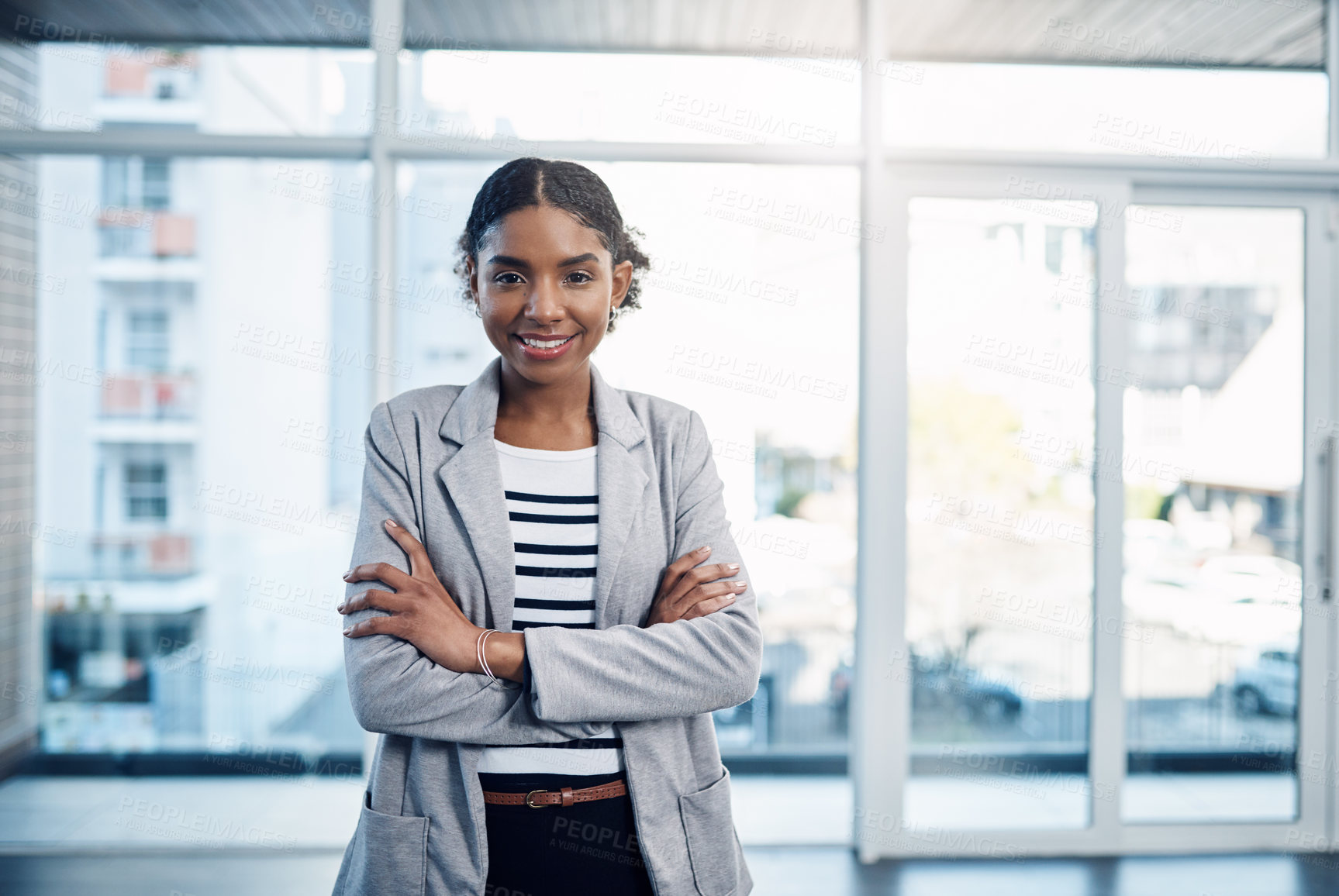 Buy stock photo Confident, proud and professional young black business woman folding her arms and smiling in a modern office. Portrait of African American leader looking powerful, successful standing in power stance