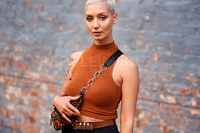Buy stock photo Cropped portrait of an attractive young woman looking serious while standing against a brick wall outdoors