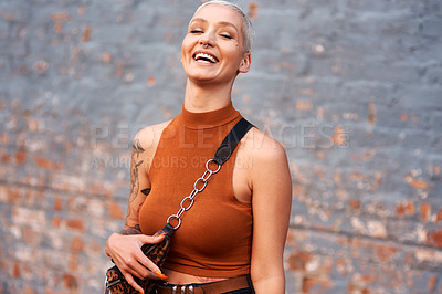 Buy stock photo Cropped shot of an attractive young woman laughing while standing against a brick wall outdoors