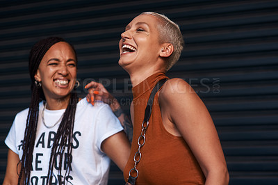 Buy stock photo Cropped shot of two attractive young girlfriends laughing together while standing against a dark background