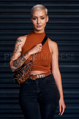 Buy stock photo Cropped portrait of an attractive young woman looking serious while standing against a dark background