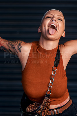 Buy stock photo Cropped shot of an attractive young woman sticking out her tongue while standing with her arms outstretched against a dark background