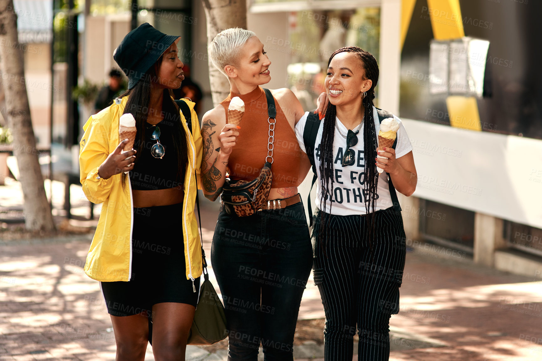 Buy stock photo Shot of three friends enjoying ice cream cones while out in the city