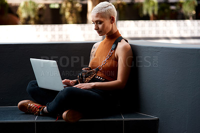Buy stock photo Full length shot of an attractive young woman sitting down and using her laptop outdoors