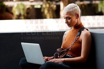 Buy stock photo Shot of an attractive young woman using a laptop while relaxing outdoors