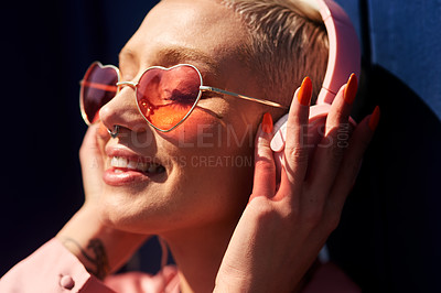Buy stock photo Cropped shot of an attractive young woman standing against a blue wall and listening to music through headphones