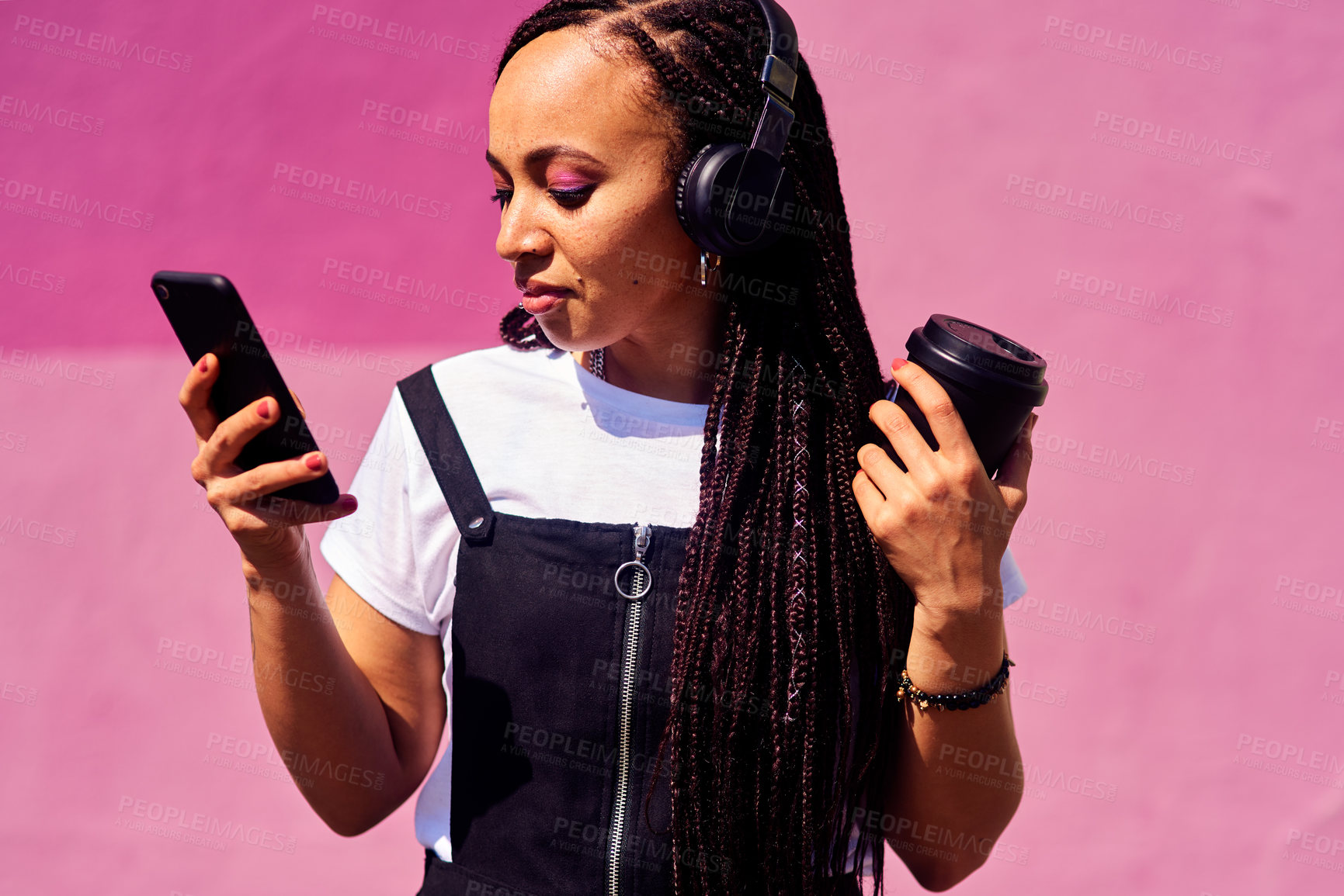 Buy stock photo Woman, headphones and outdoor on phone or coffee, streaming sound and subscription by pink background. Female person, latte and listening to podcast or online for social media, app and travel in city