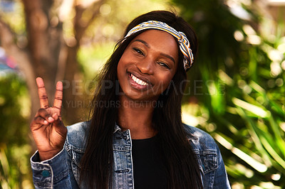 Buy stock photo Portrait of an attractive young woman making the peace sign while relaxing in a park outdoors