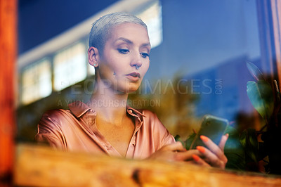 Buy stock photo Shot of an attractive young woman using her cellphone while relaxing inside a local cafe