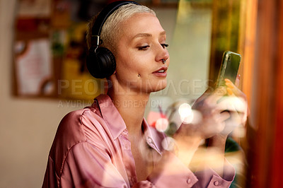 Buy stock photo Woman, phone and headphones in cafe, social media and listening to music on app to relax. Female person, restaurant and mobile internet for search online, podcast and dating website or song audio