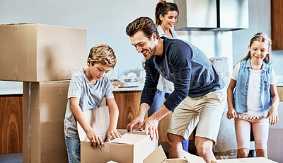 Buy stock photo Cropped shot of a cheerful young family of four working together to unpack boxes in their new home on moving day