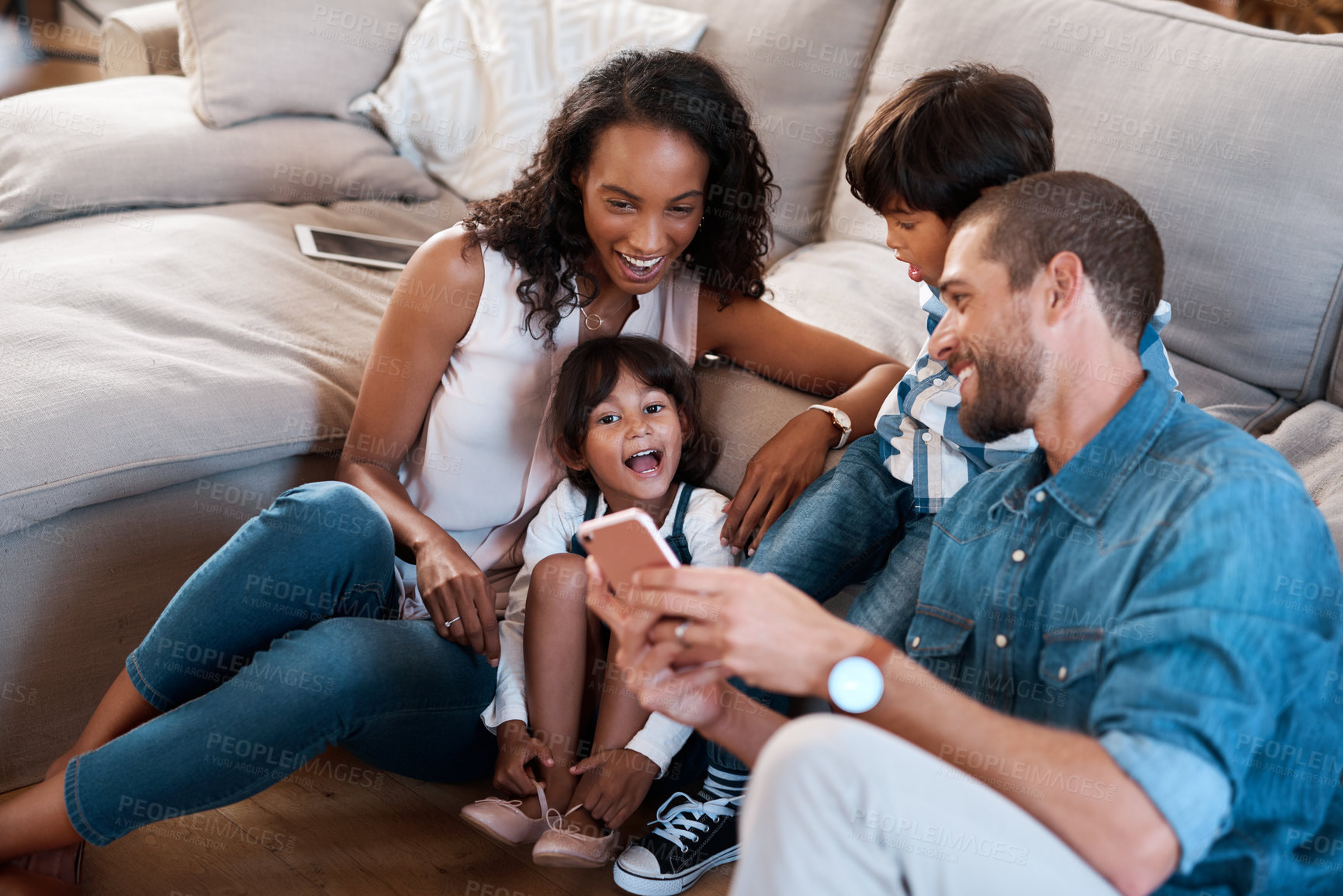 Buy stock photo Shot of a family of four watching something on a cellphone