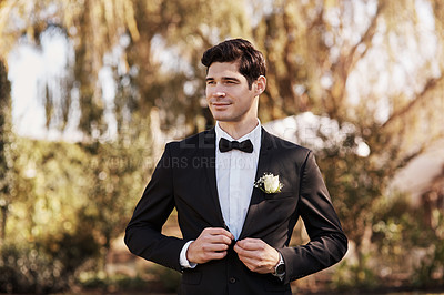 Buy stock photo Cropped shot of a handsome young bridegroom looking thoughtful while adjusting his suit on his wedding day