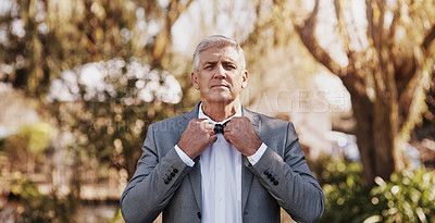 Buy stock photo Cropped portrait of a handsome mature bridegroom adjusting his necktie while preparing for his wedding outdoors