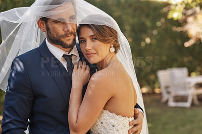 Buy stock photo Cropped shot of an affectionate young newlywed couple embracing each other while covering themselves with a veil on their wedding day