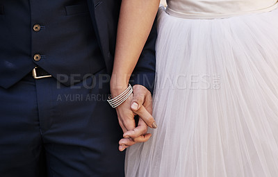 Buy stock photo Cropped shot of an unrecognizable newlywed couple holding hands while standing outdoors on their wedding day