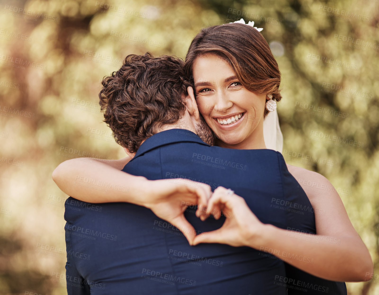 Buy stock photo Cropped shot of an affectionate young bride smiling while making a heart shape on her groom's back on their wedding day