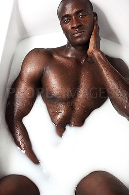 Buy stock photo Shot of a muscular young man having a milky bath at home